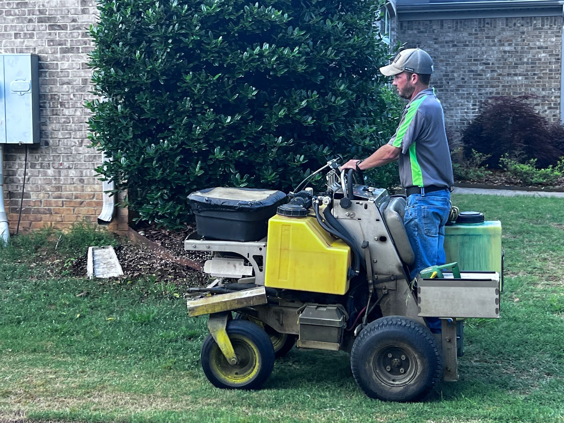A man is riding a lawn mower on a lush green lawn.