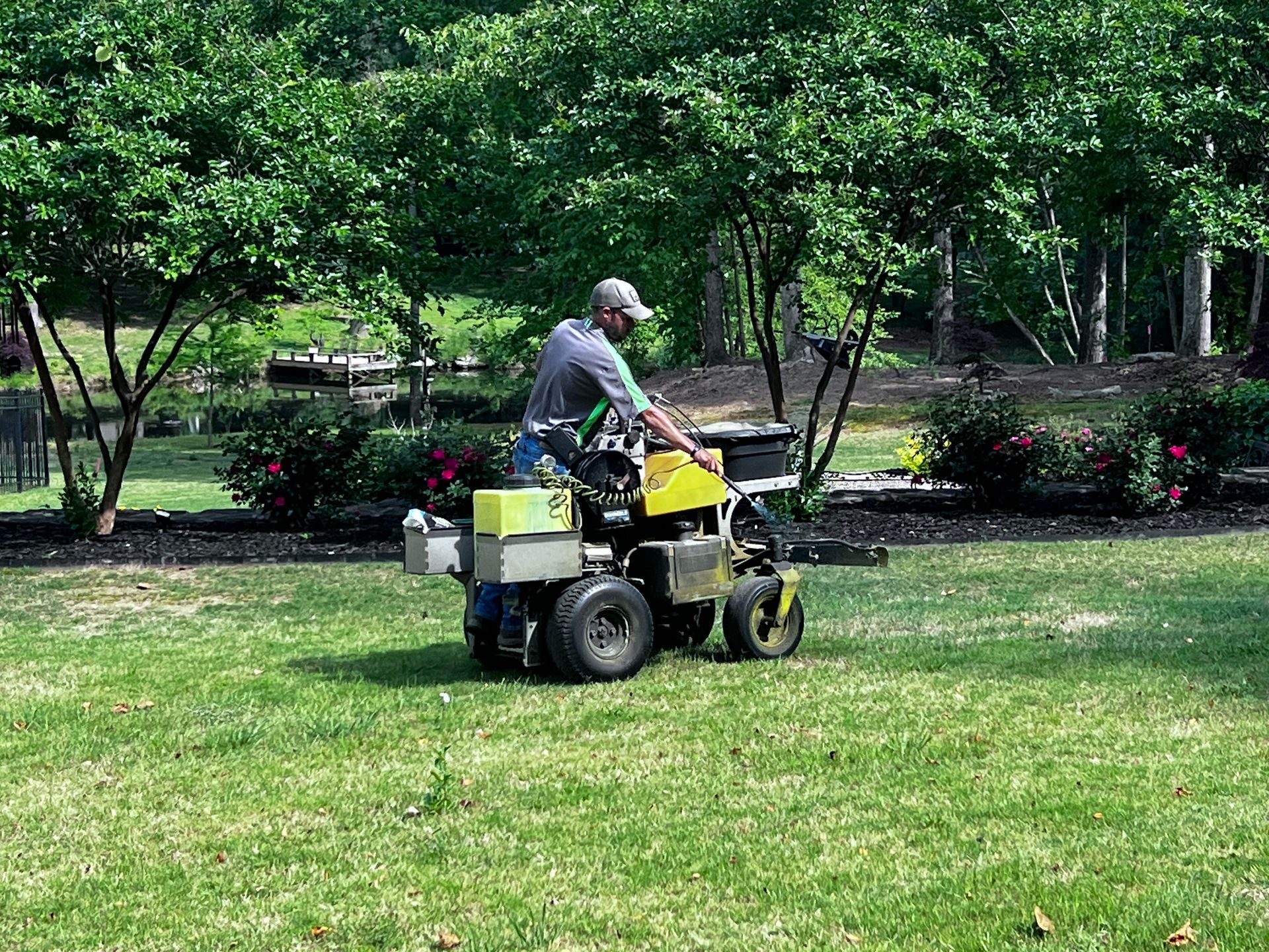 A man is riding a lawn mower on a lush green lawn.