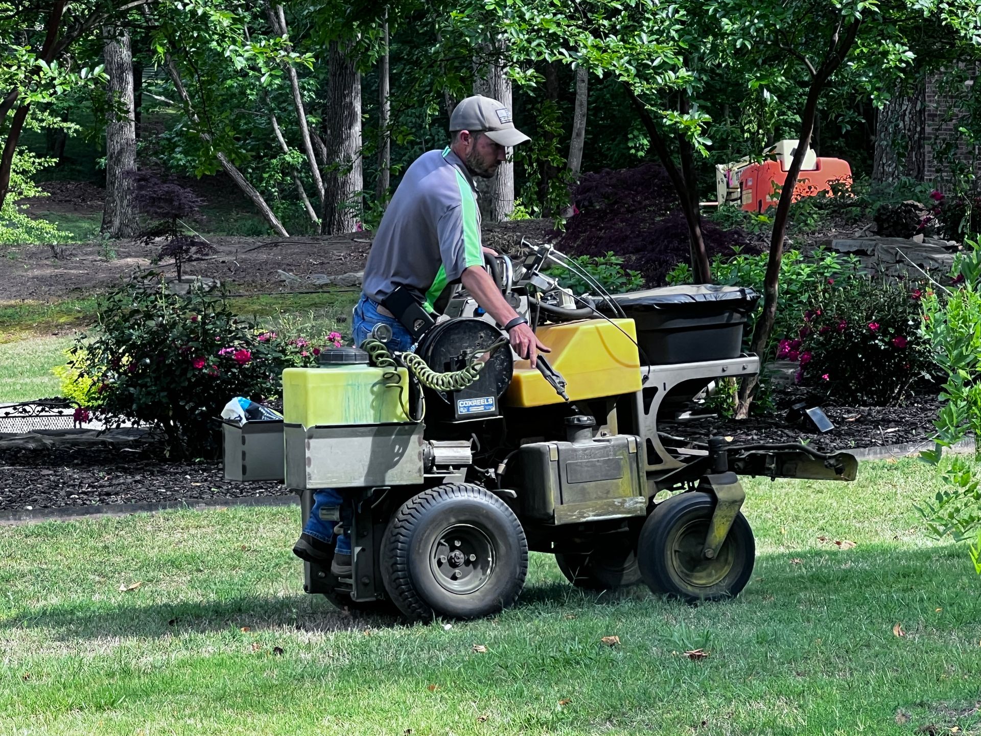 A man is riding a yellow lawn mower on a lush green lawn.