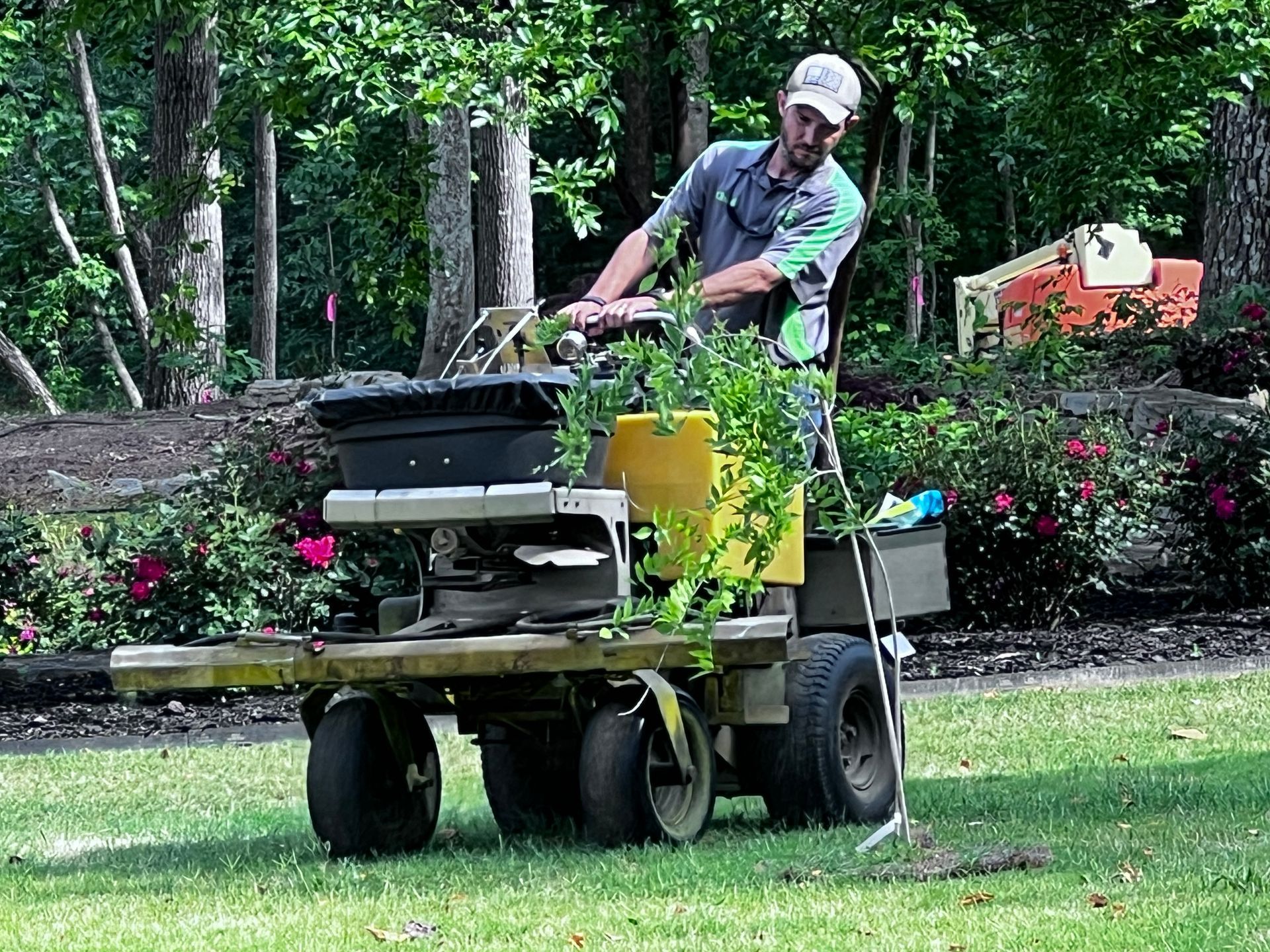 A man is riding a lawn mower on a lush green lawn.