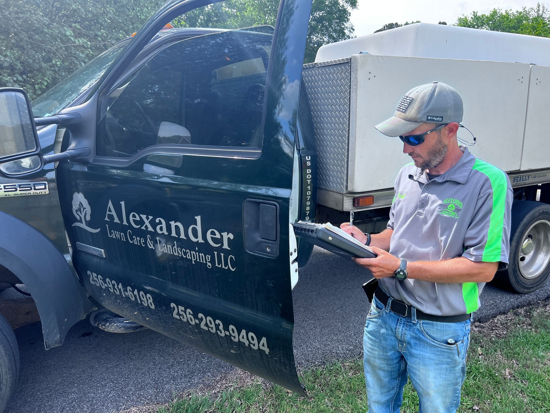 A man is standing in front of a truck holding a clipboard.