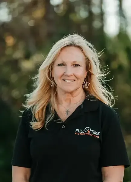 Woman with blonde hair wearing a black polo shirt, smiling outdoors.