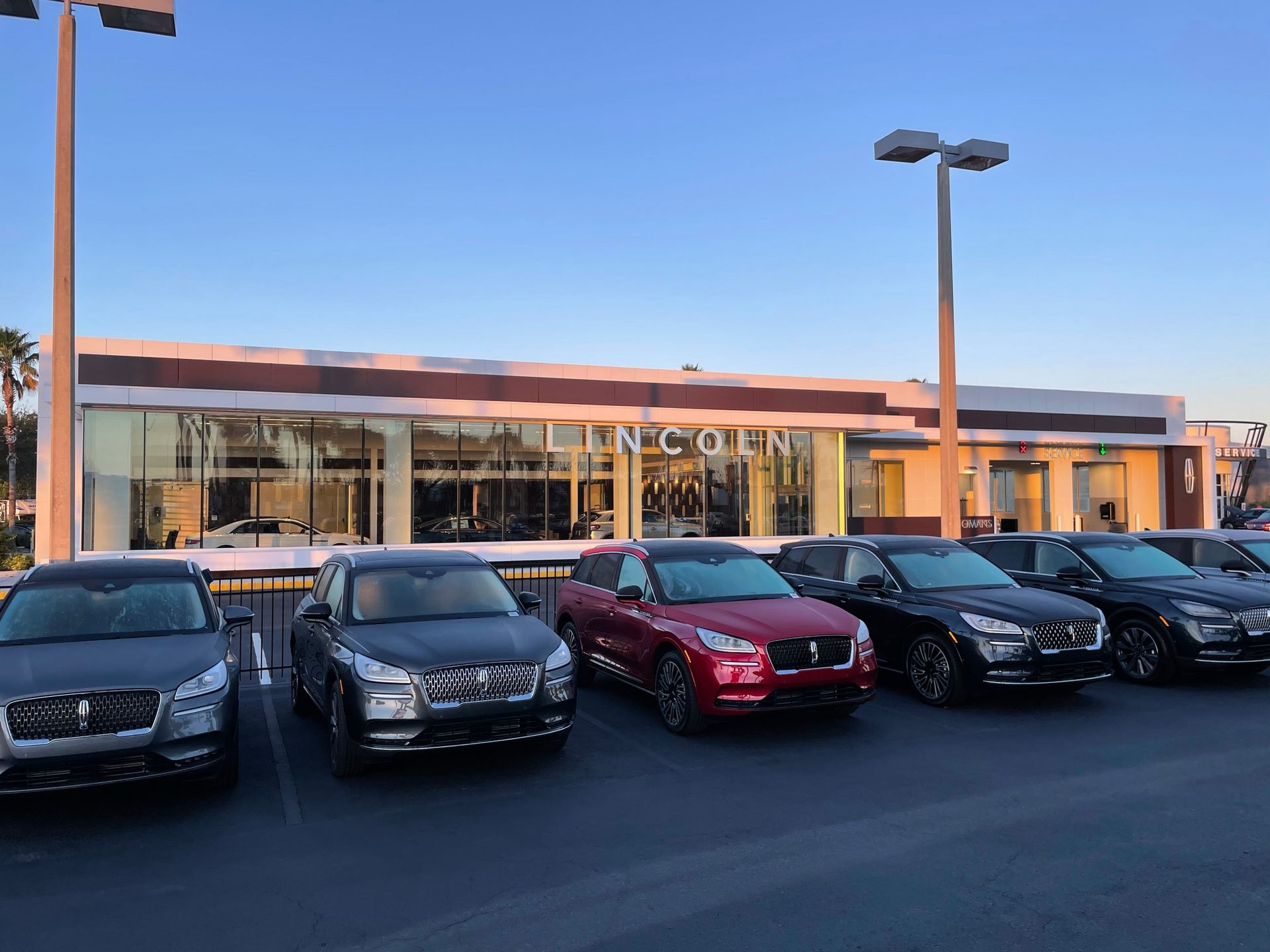 A Lincoln car dealership with several luxury SUVs parked in the lot under a clear sky.