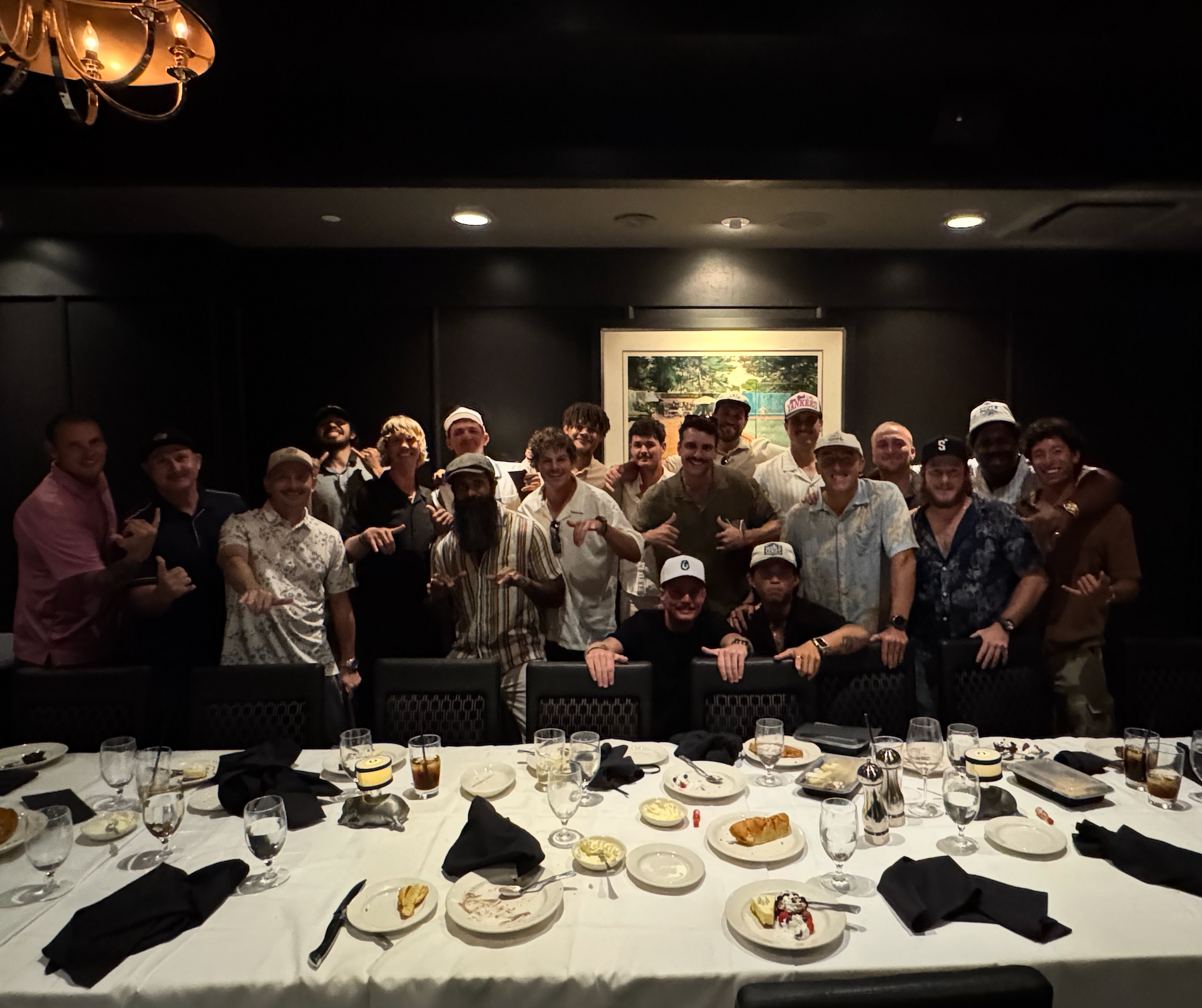 Man spraying pesticides on bushes and grass in a yard, wearing a hat, safety glasses, and gloves.