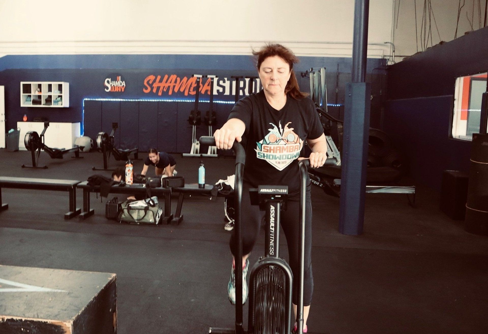 A woman is riding an exercise bike in a gym.