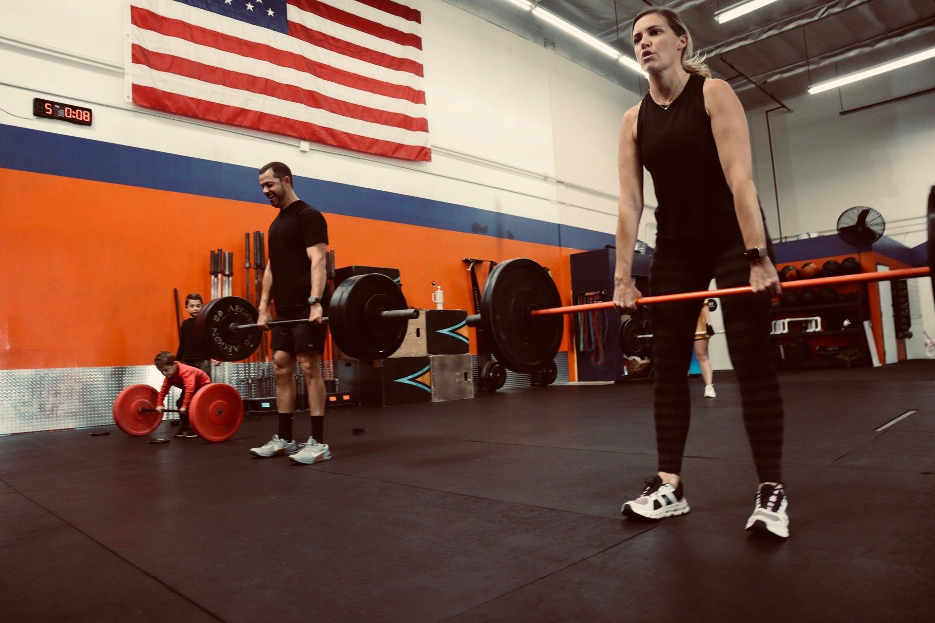 A man and a woman are lifting weights in a gym.