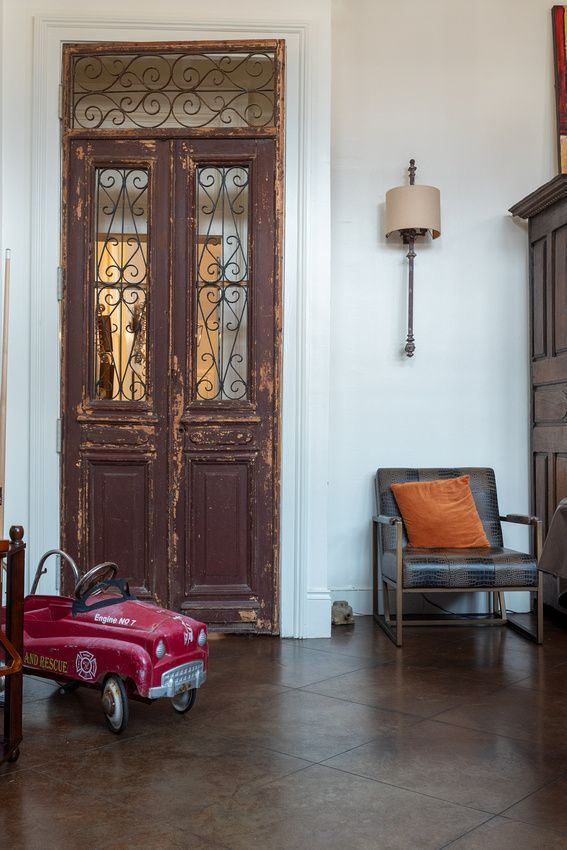 A red toy car is parked in front of a door in a living room.