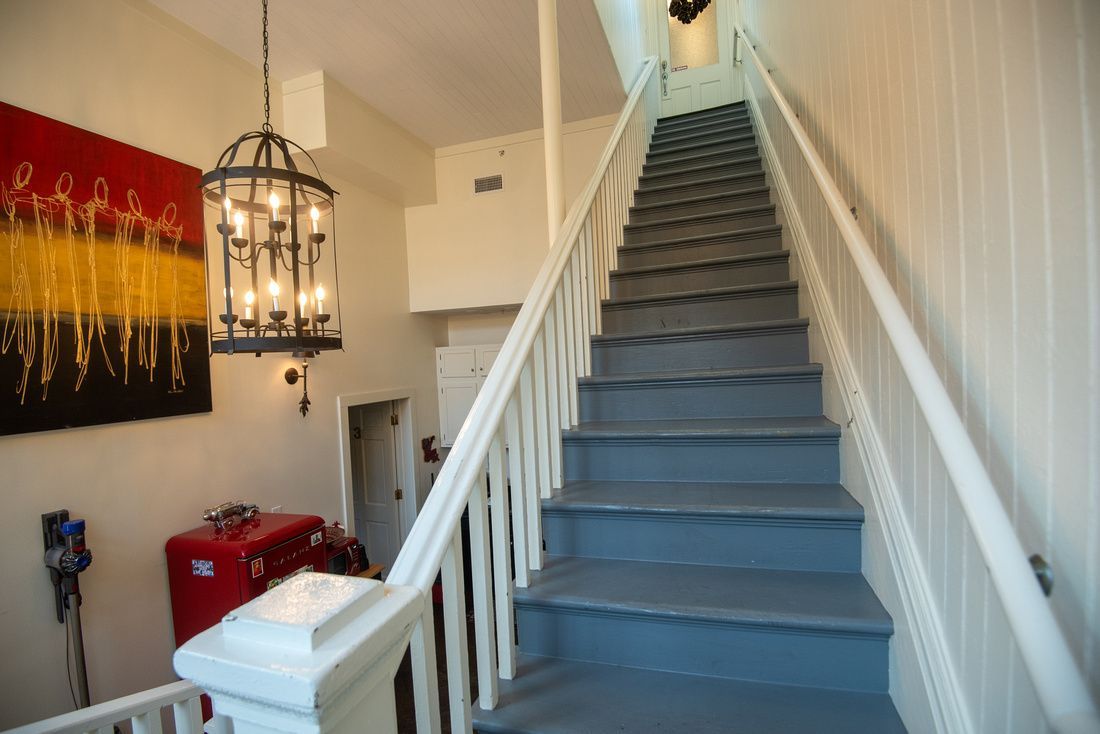 A staircase with a white railing and a chandelier hanging from the ceiling.