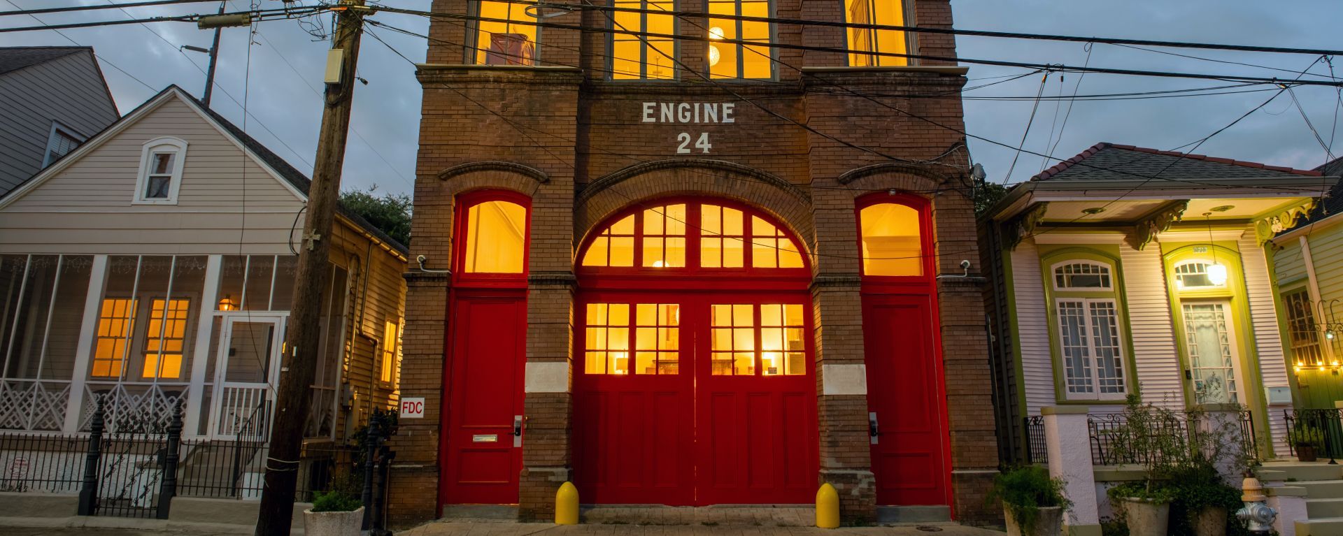 A fire station with red doors and windows is surrounded by houses.