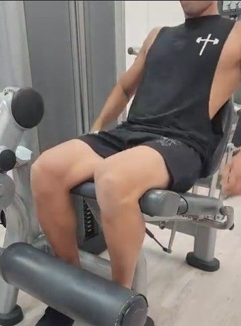 A Man is Sitting on a Leg Extension Machine in a Gym —True Form Fitness In Gwandalan, NSW