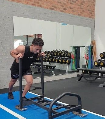 A Man is Pushing a Sled in a Gym —True Form Fitness In Gwandalan, NSW