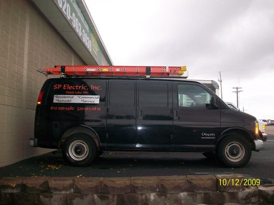 A black van for sp electric inc. is parked in front of a building
