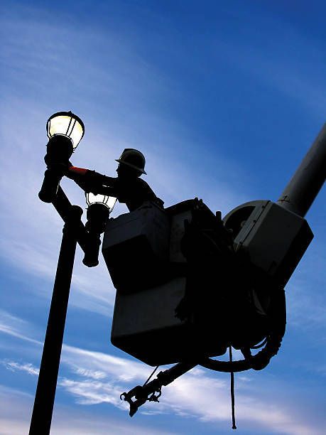 A silhouette of a man working on a street light