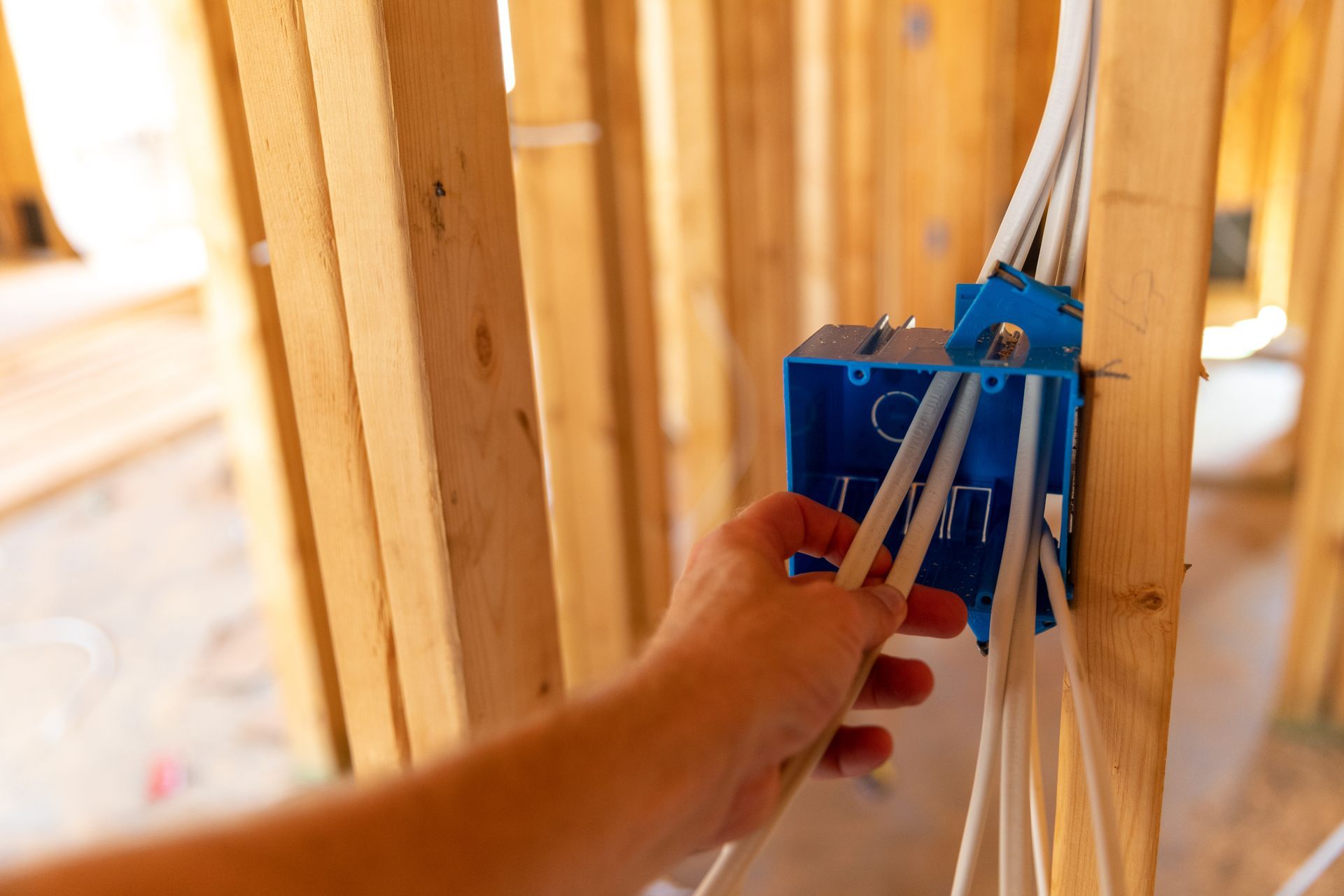 A person is installing electrical wires in a house under construction.