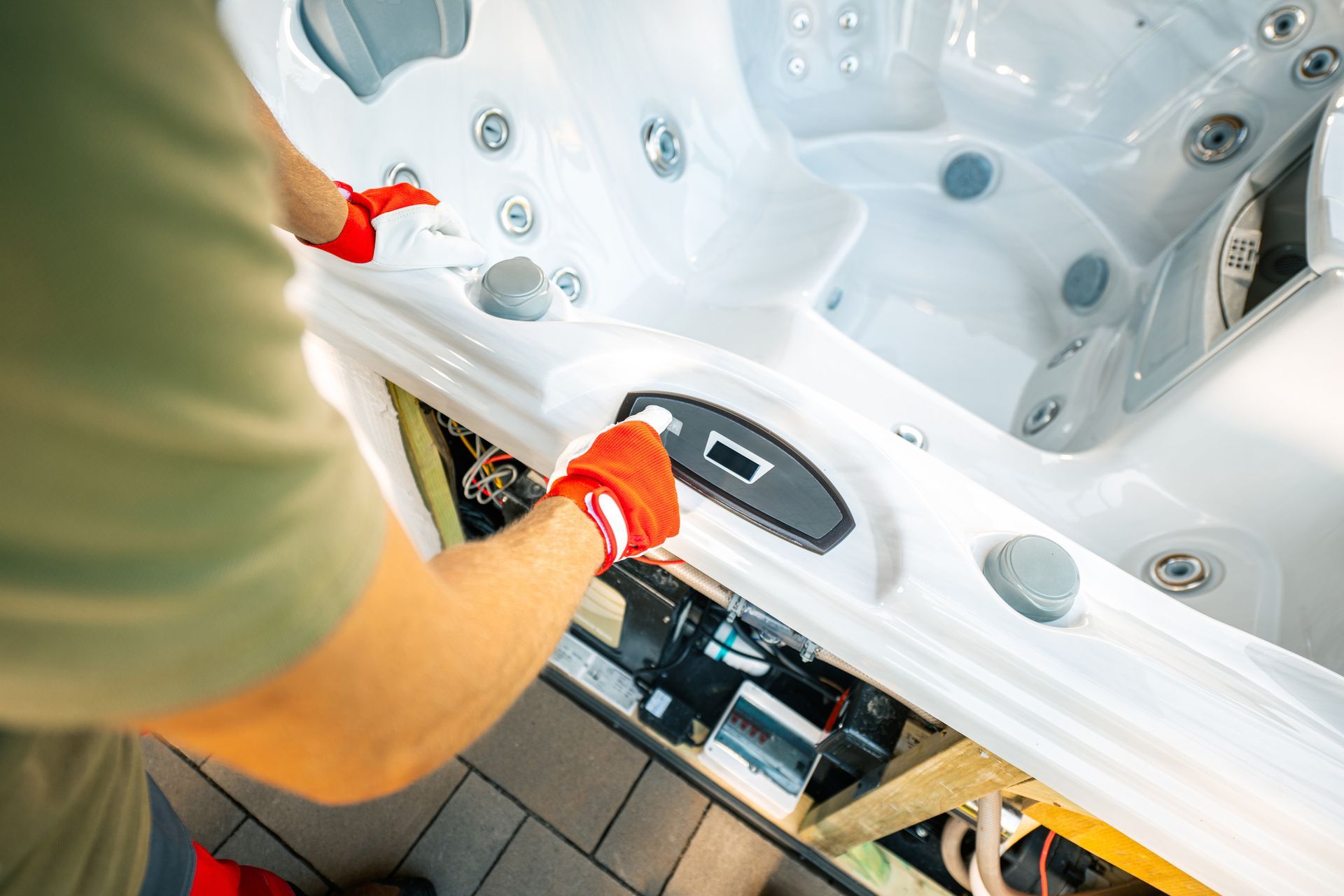 A man in red gloves is working on a hot tub.