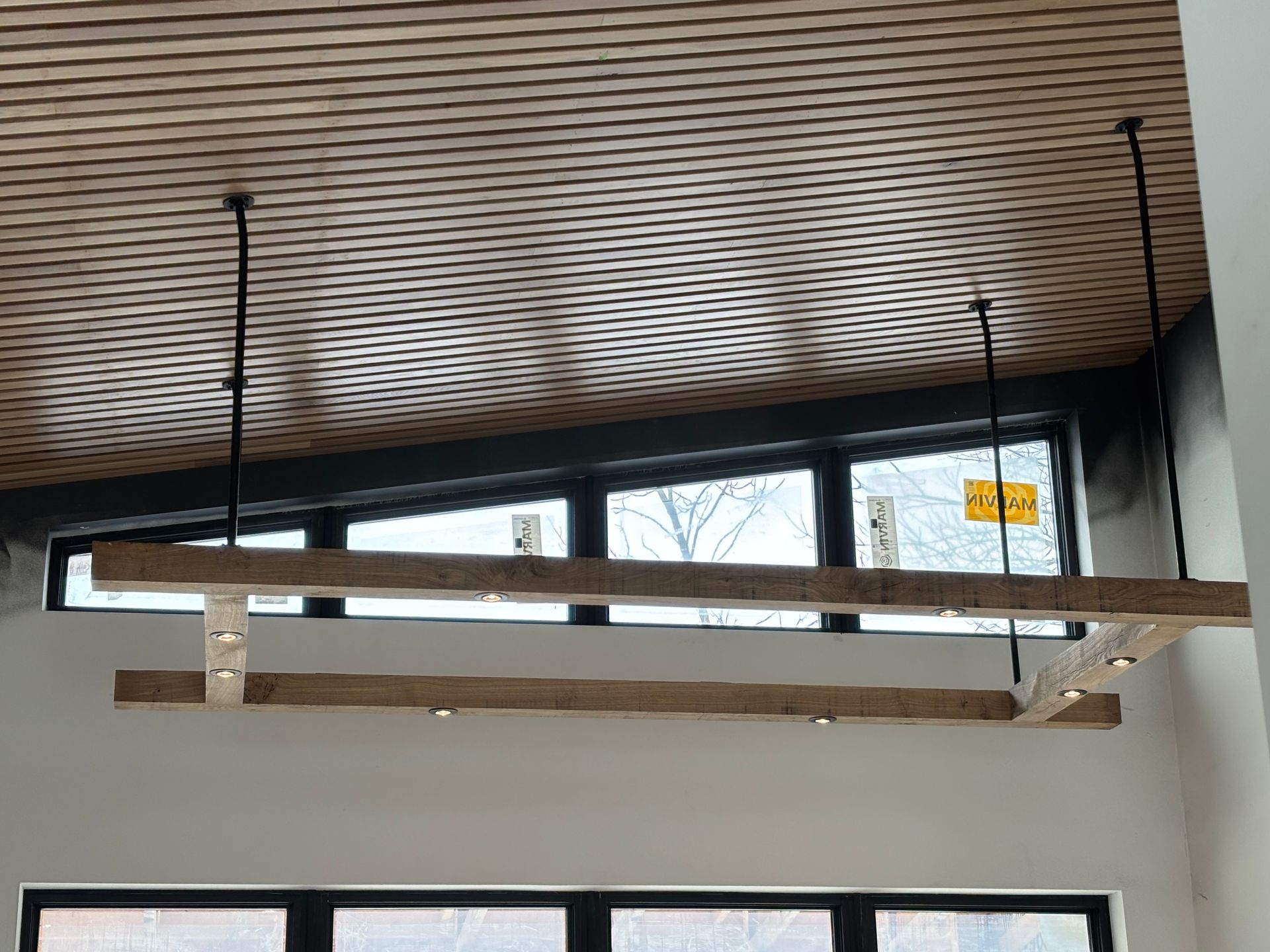 A wooden beam is hanging from the ceiling of a room with a window.