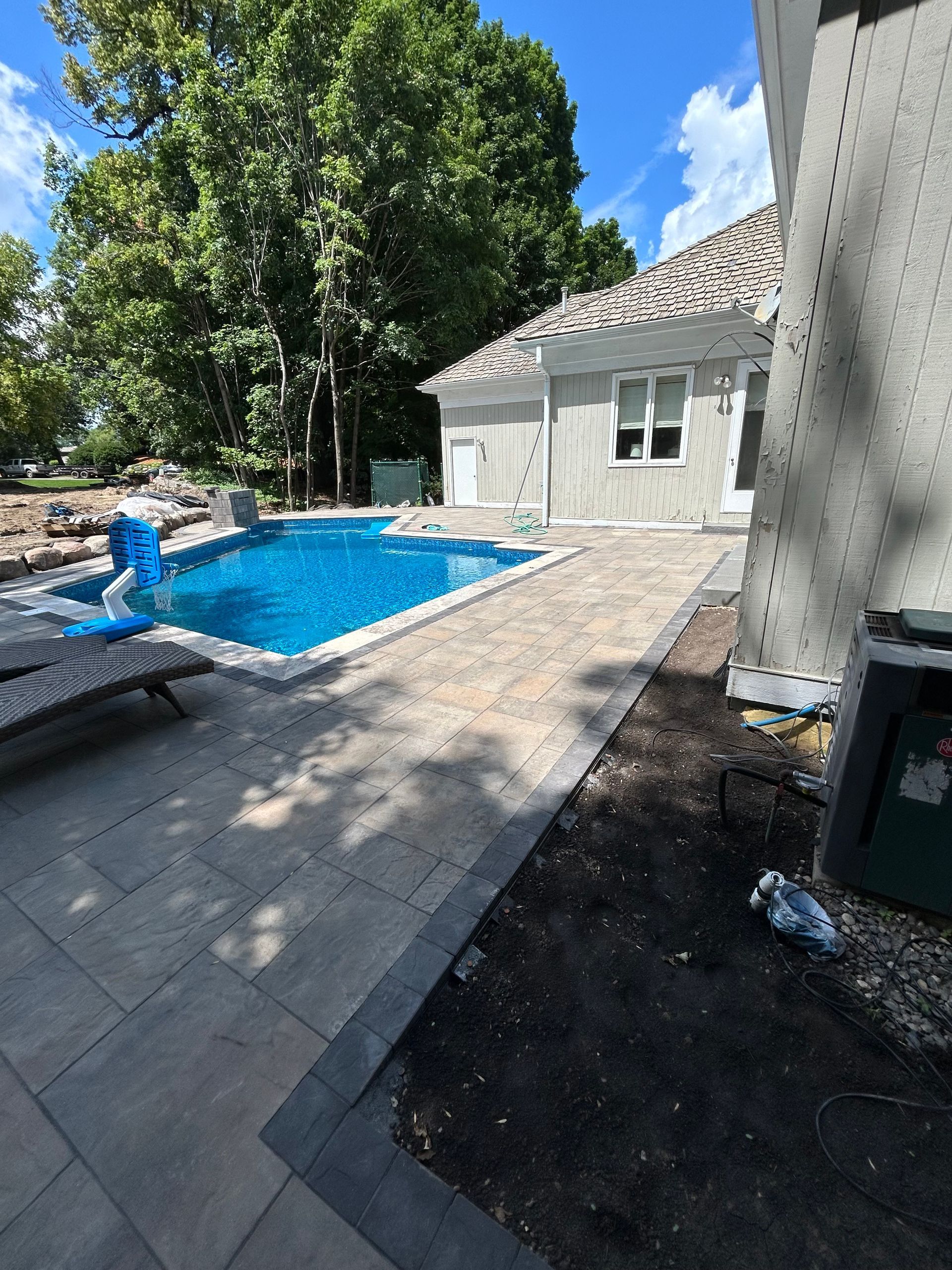 A large swimming pool is in the backyard of a house.