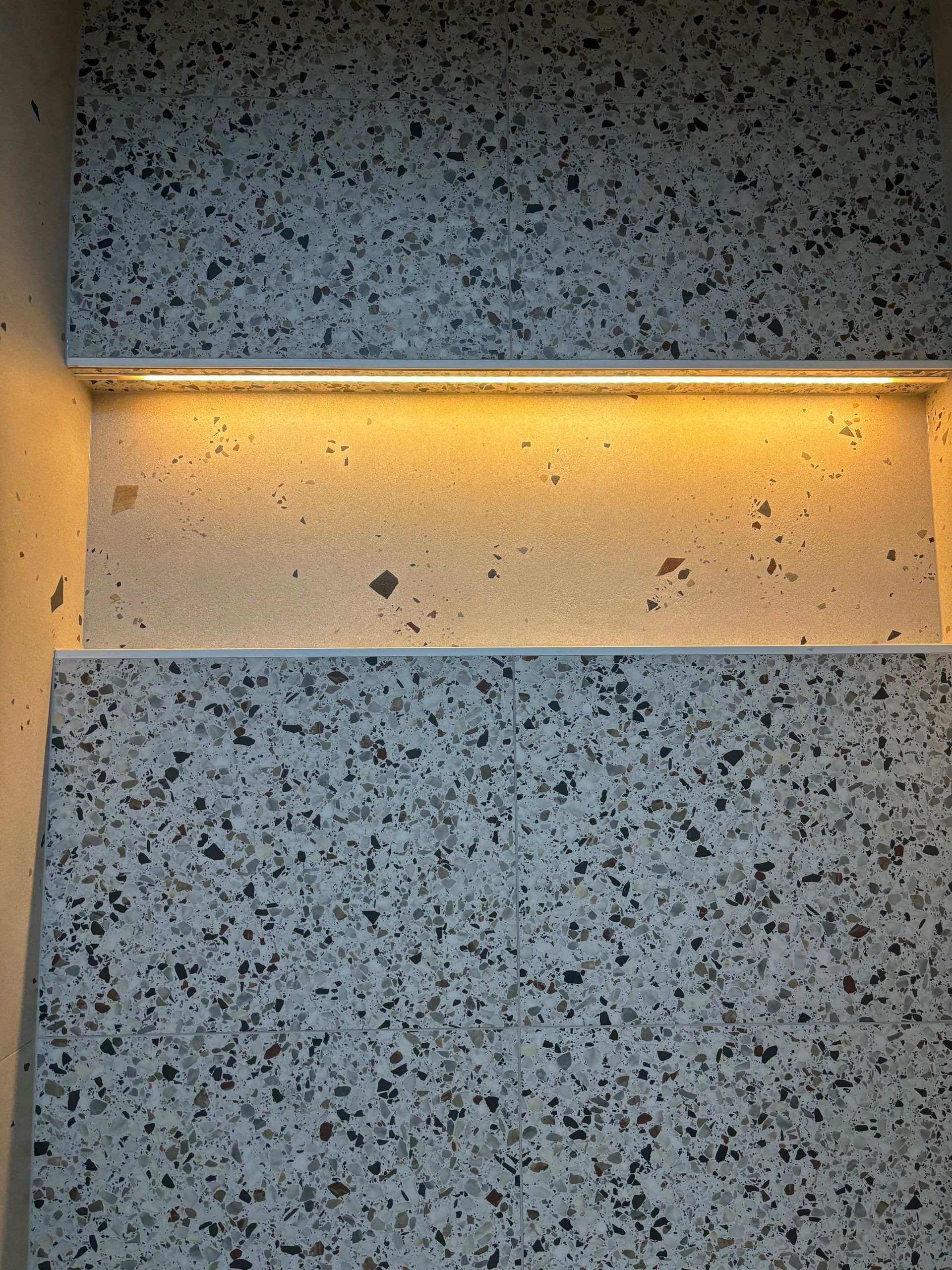 A wall with a shelf and a light on it