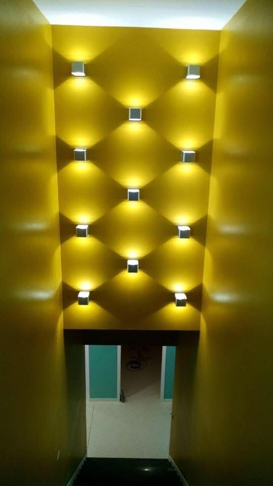 A hallway with yellow walls and lights on the wall.