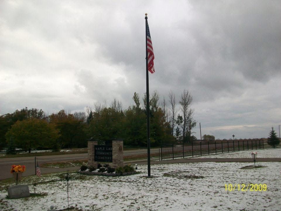 An american flag is flying in a cemetery on a cloudy day