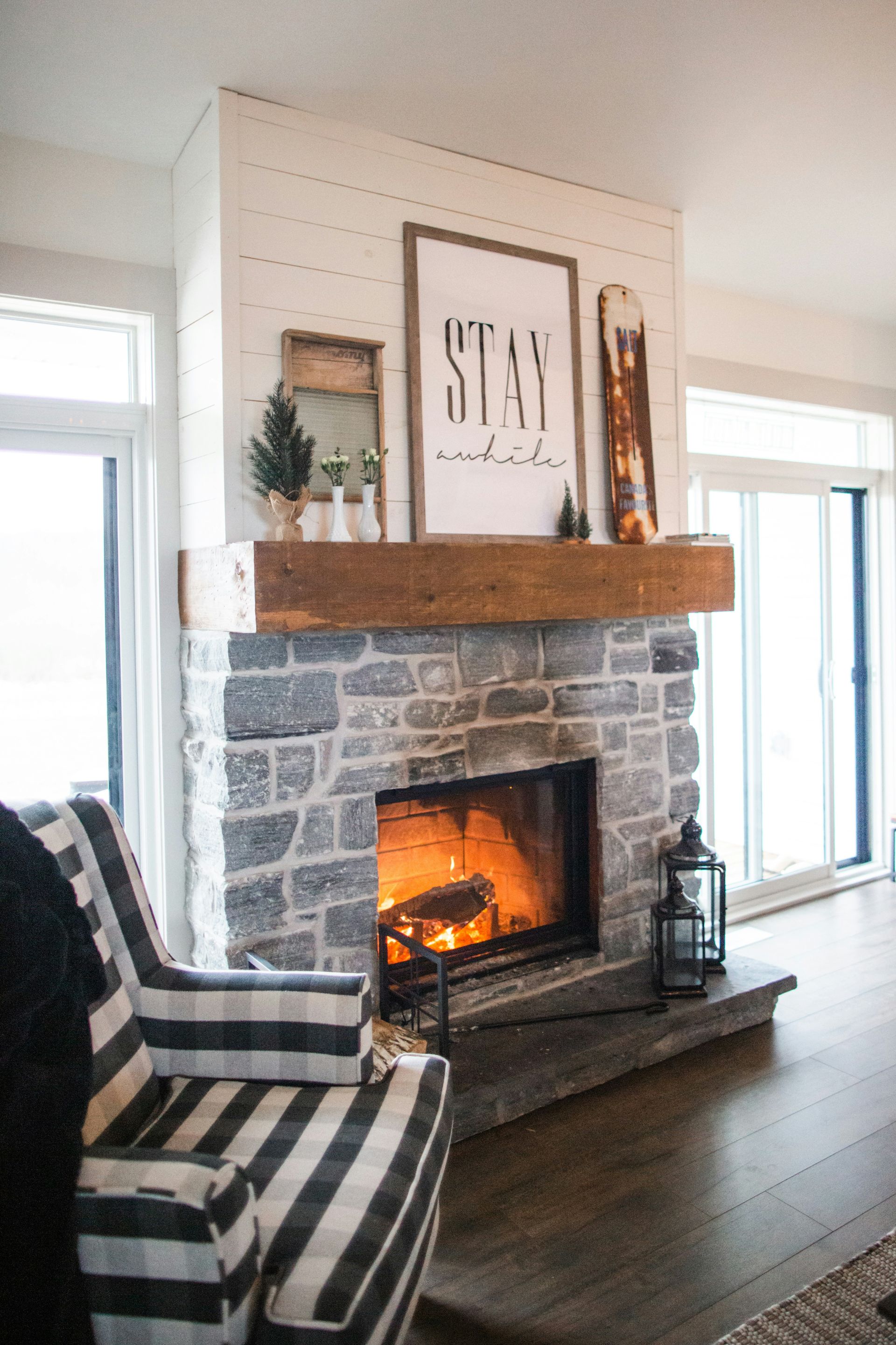 A living room with a stone fireplace and a striped chair.