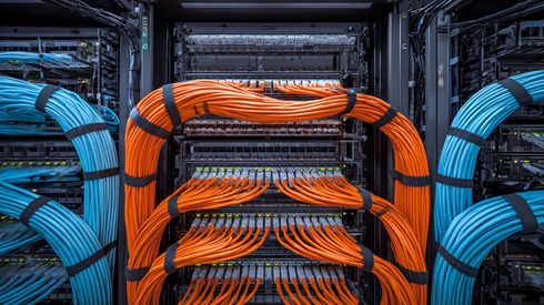 Blue and orange network cables bundled inside a server rack.