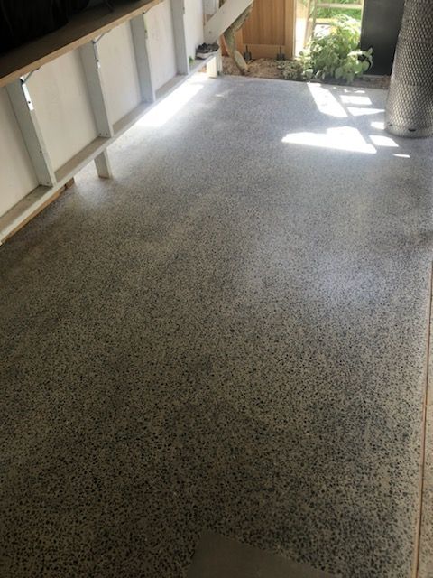 A Man Is Using A Trowel To Level A Concrete Floor — Fantastic Frank's Concrete Resurfacing In Byron Bay, NSW