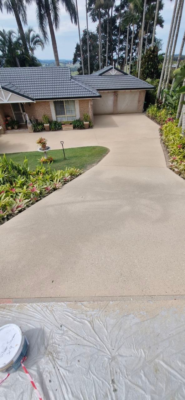 A Person Is Using A Mop To Spread Concrete On A Sidewalk — Fantastic Frank's Concrete Resurfacing In Byron Bay, NSW