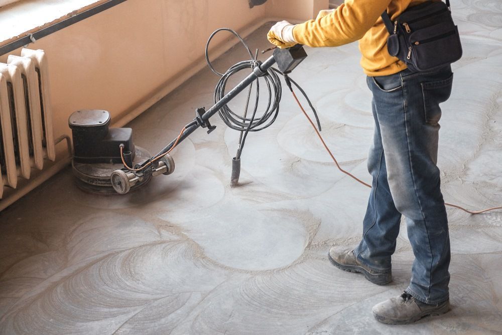 A Man Is Using A Machine To Sand A Concrete Floor  — Fantastic Frank's Concrete Resurfacing In Tweed Heads, NSW
