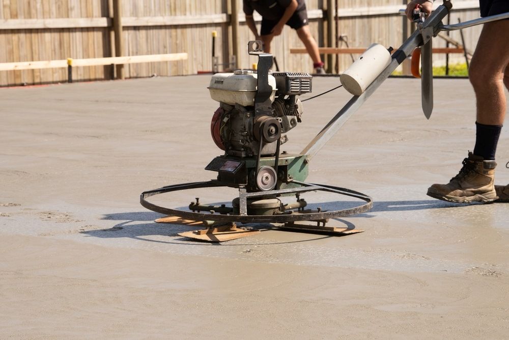 A Man Is Using A Machine To Level A Concrete Floor — Fantastic Frank's Concrete Resurfacing In Byron Bay, NSW