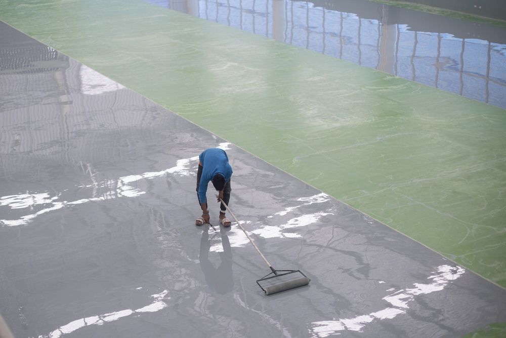 A Man Is Cleaning The Floor Of A Building With A Broom — Fantastic Frank's Concrete Resurfacing In Byron Bay, NSW