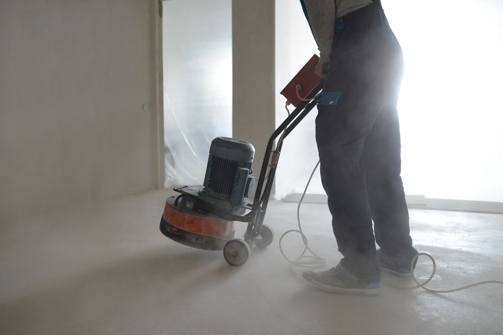 A Man Is Grinding A Concrete Floor With A Machine — Fantastic Frank's Concrete Resurfacing In Ballina, NSW