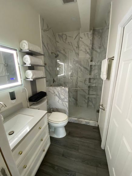 A bathroom with a toilet , sink , mirror and walk in shower.