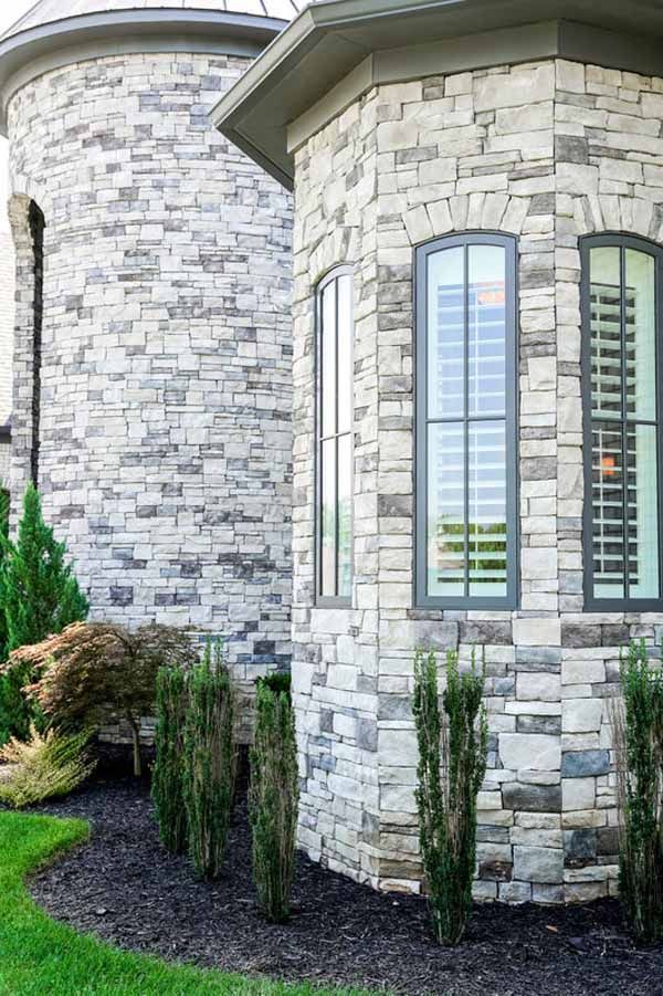 A large brick building with a lot of windows and bushes in front of it.