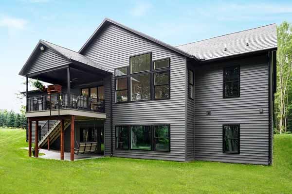 A large house with a lot of windows is sitting on top of a lush green field.