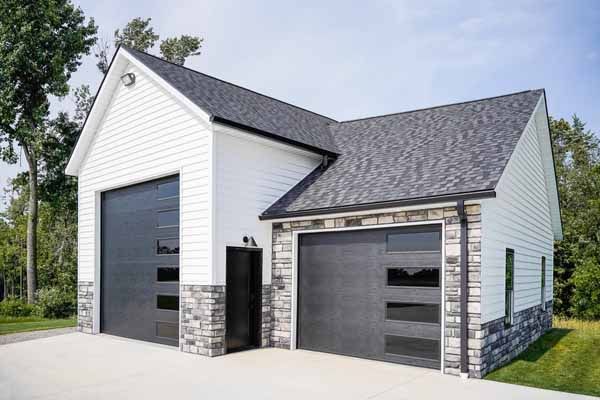 A white house with a black garage door and a black roof.