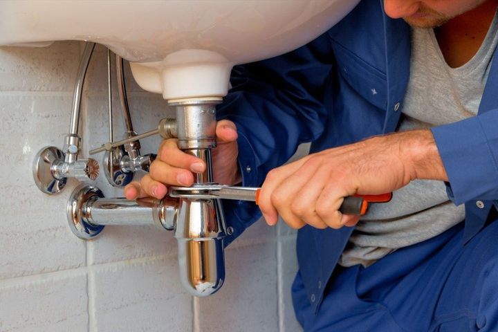 idraulico con pappagallo impegnato a stringere la guarnizione di un tubo