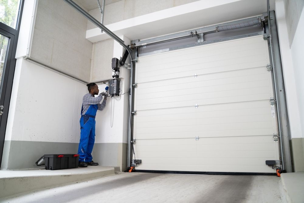 A man is working on a garage door in a garage.