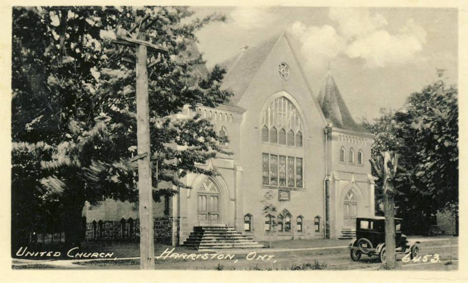 A black and white photo of a church with a car parked in front of it