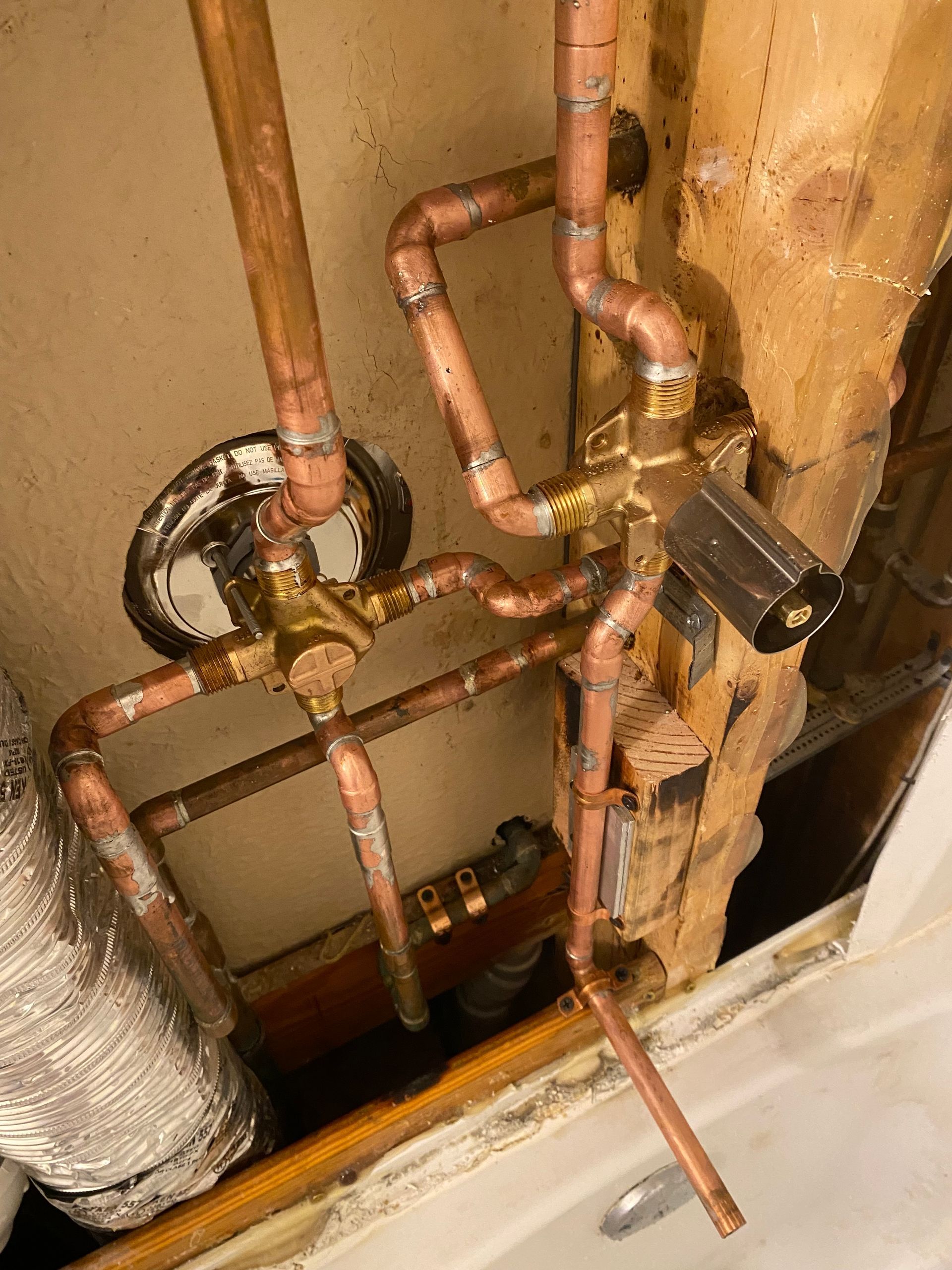 A close up of copper pipes in a bathroom.