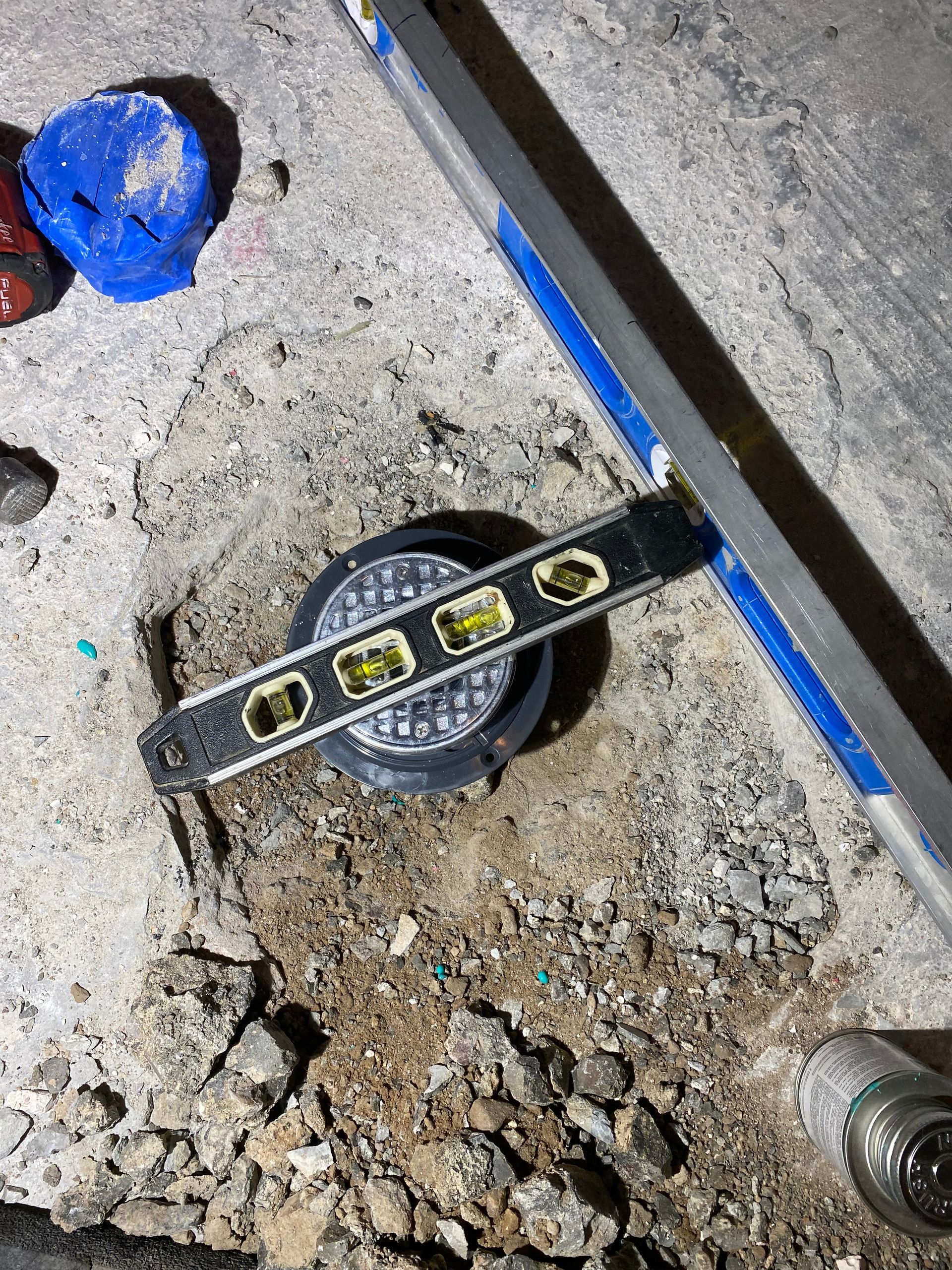 A level is sitting on the ground next to a manhole cover.