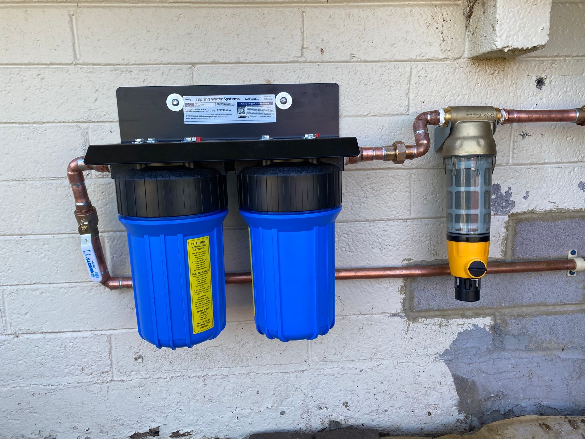 A water filter is attached to a brick wall