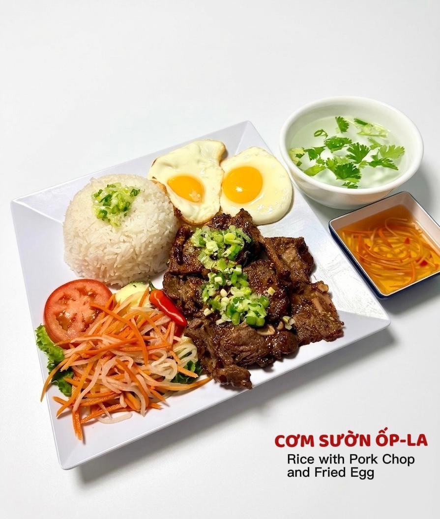 A plate of Vietnamese rice with grilled pork chop, two fried eggs, shredded carrots, tomato, and a side of dipping sauce.