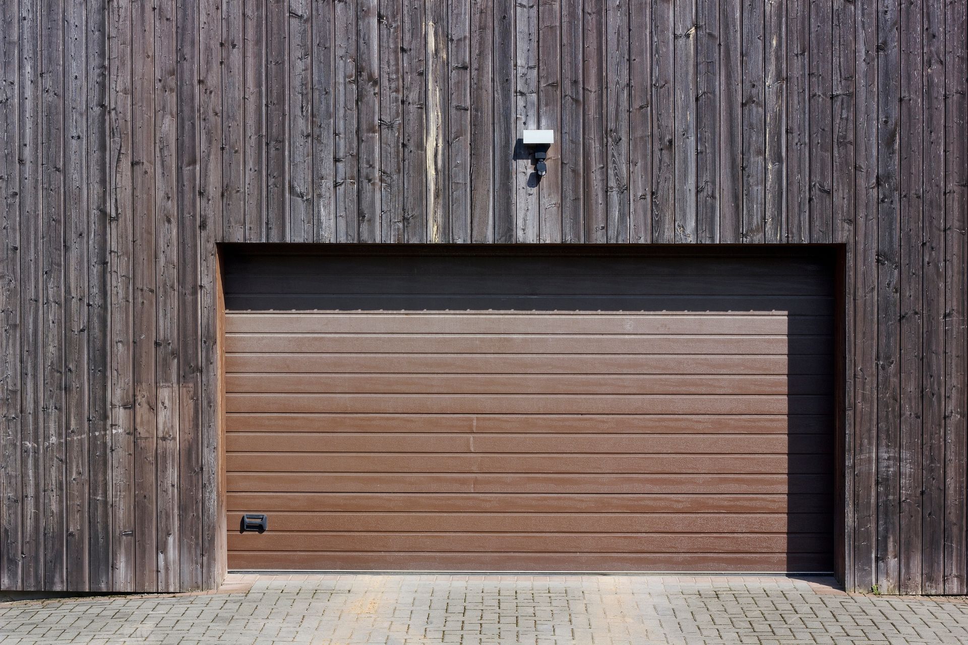 A wooden garage door is open in front of a wooden building.
