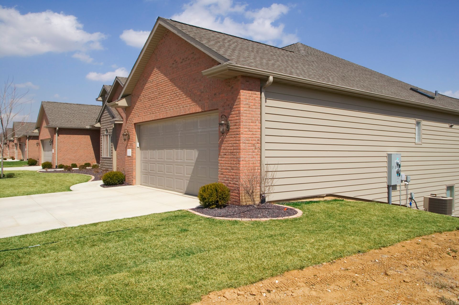 A brick house with a tan siding and a gray roof