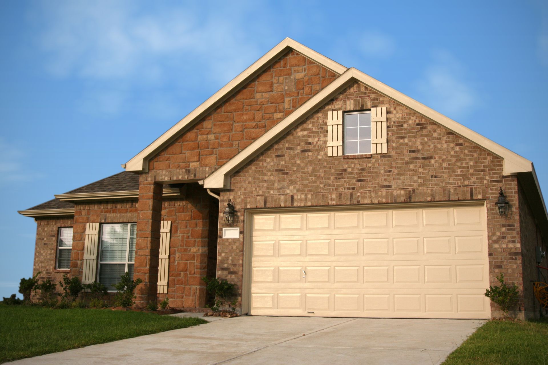 A brick house with a tan garage door and a window