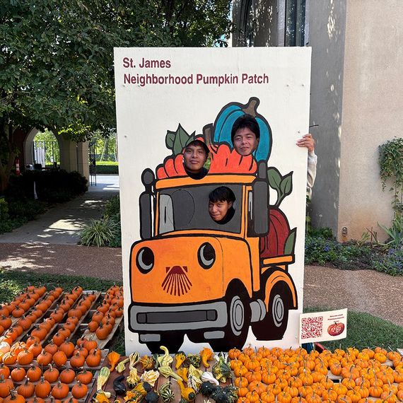 Three kids posing in a pumpkin truck cutout at St. James Pumpkin Patch. Pumpkins on display.