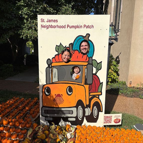 Family poses in a pumpkin patch photo cutout of a truck. Fall harvest setting, pumpkins surround.