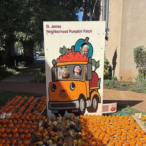 St. James neighborhood pumpkin patch with children in a truck cutout, surrounded by pumpkins.