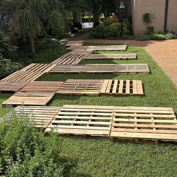 Wooden pallets laid on green grass, forming a winding path.